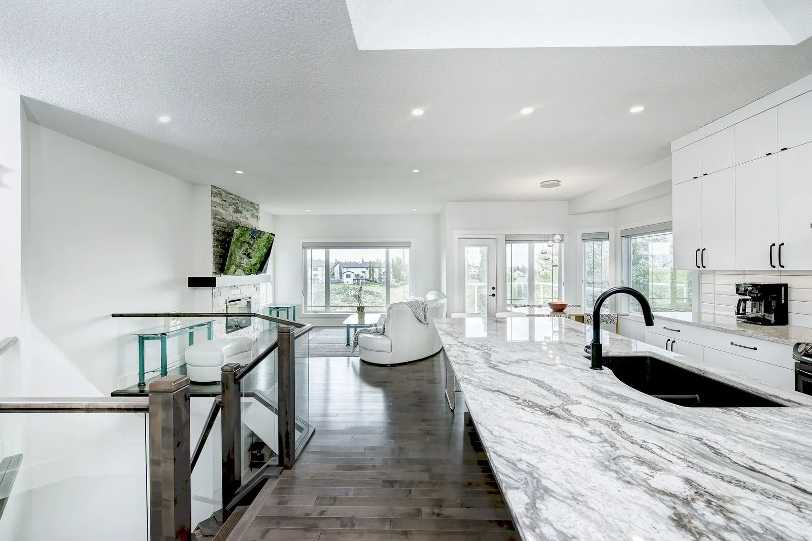 Kitchen island in veined marble with a black undermount sink, open to the living room