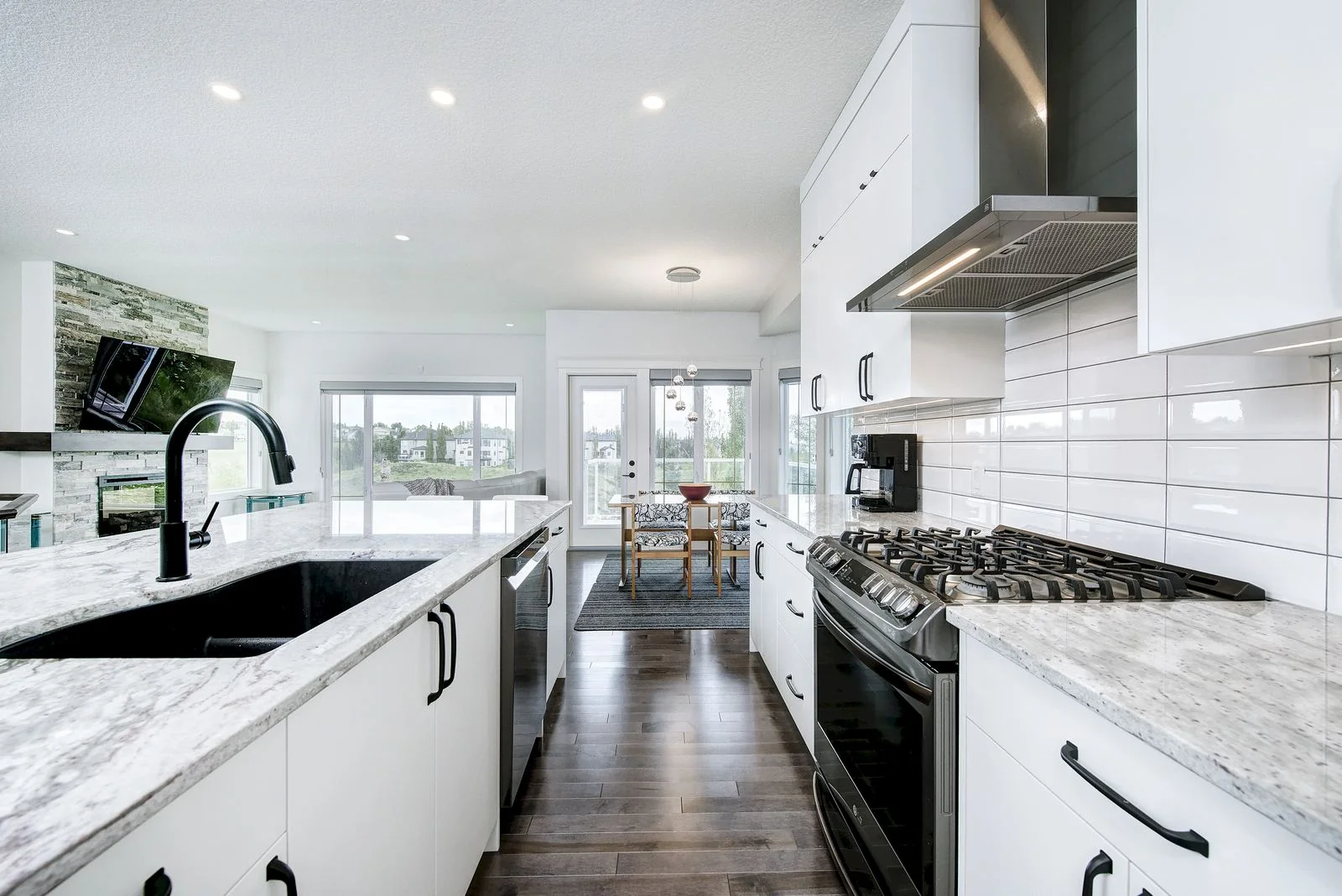 Kitchen with a gas range, white subway tile and a stainless hood