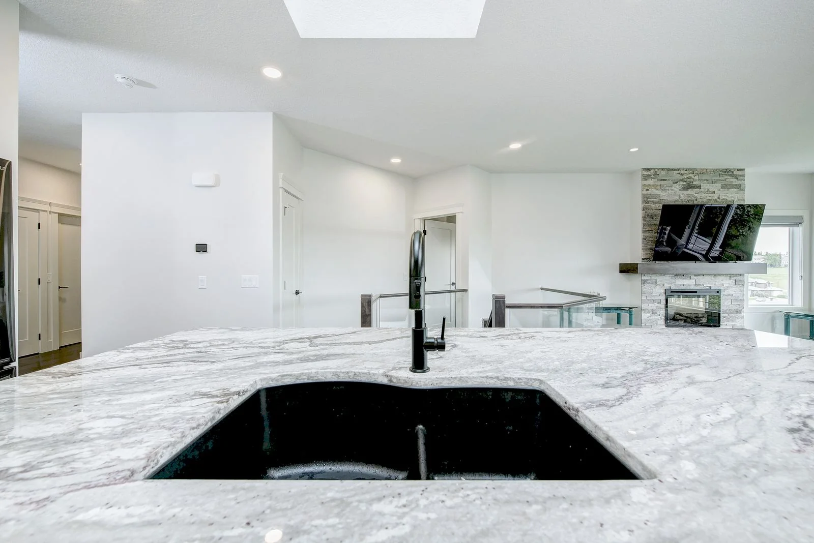 Marble island with a black sink and the fireplace beyond