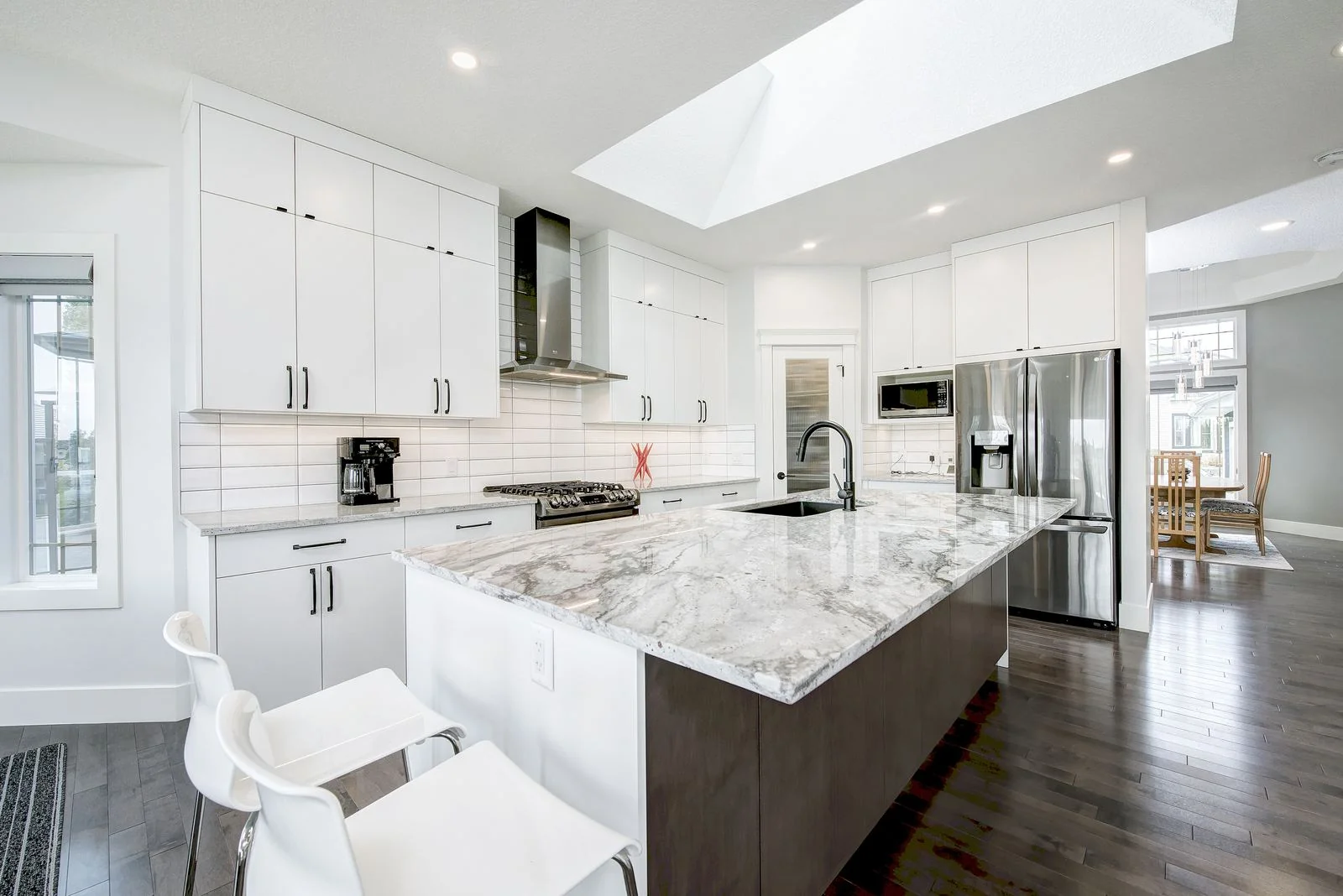 Kitchen island seating beside a stainless refrigerator