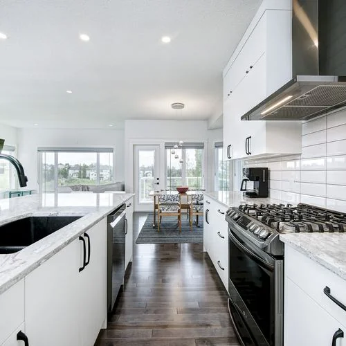 Arbour Lake, Calgary. Kitchen with a gas range, white subway tile and a stainless hood