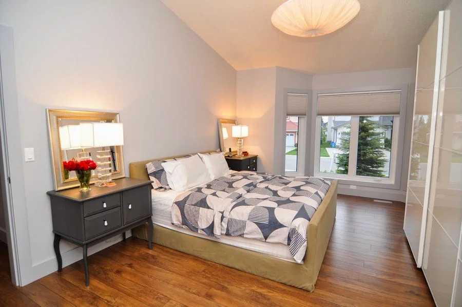 Bedroom with a patterned duvet and a mirrored dresser beside the window