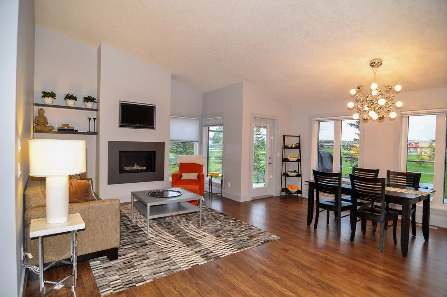 Chestermere, Alberta. Living and dining space with a fireplace and a view over open ground