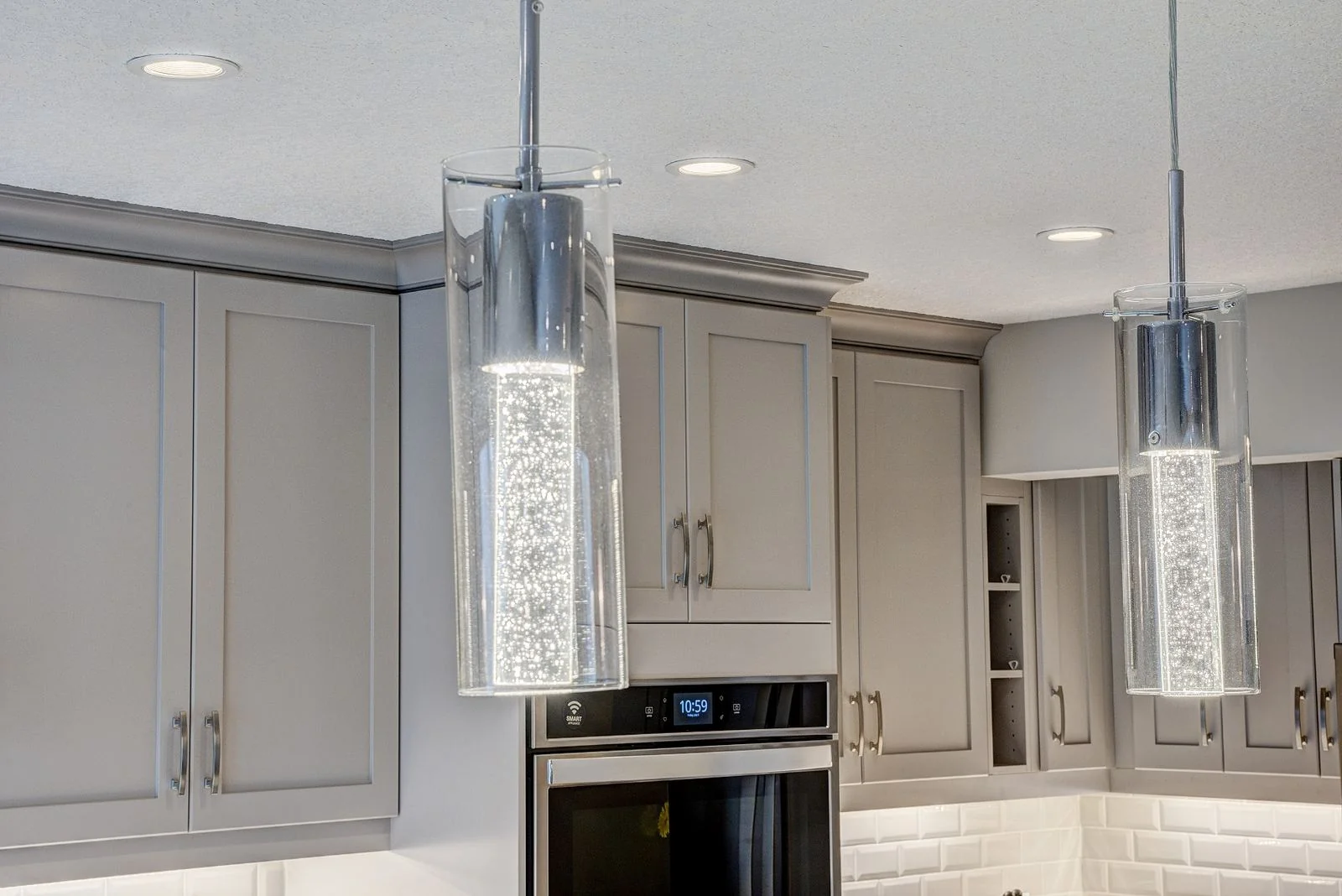 Kitchen cabinetry with a wall oven and pendant lights
