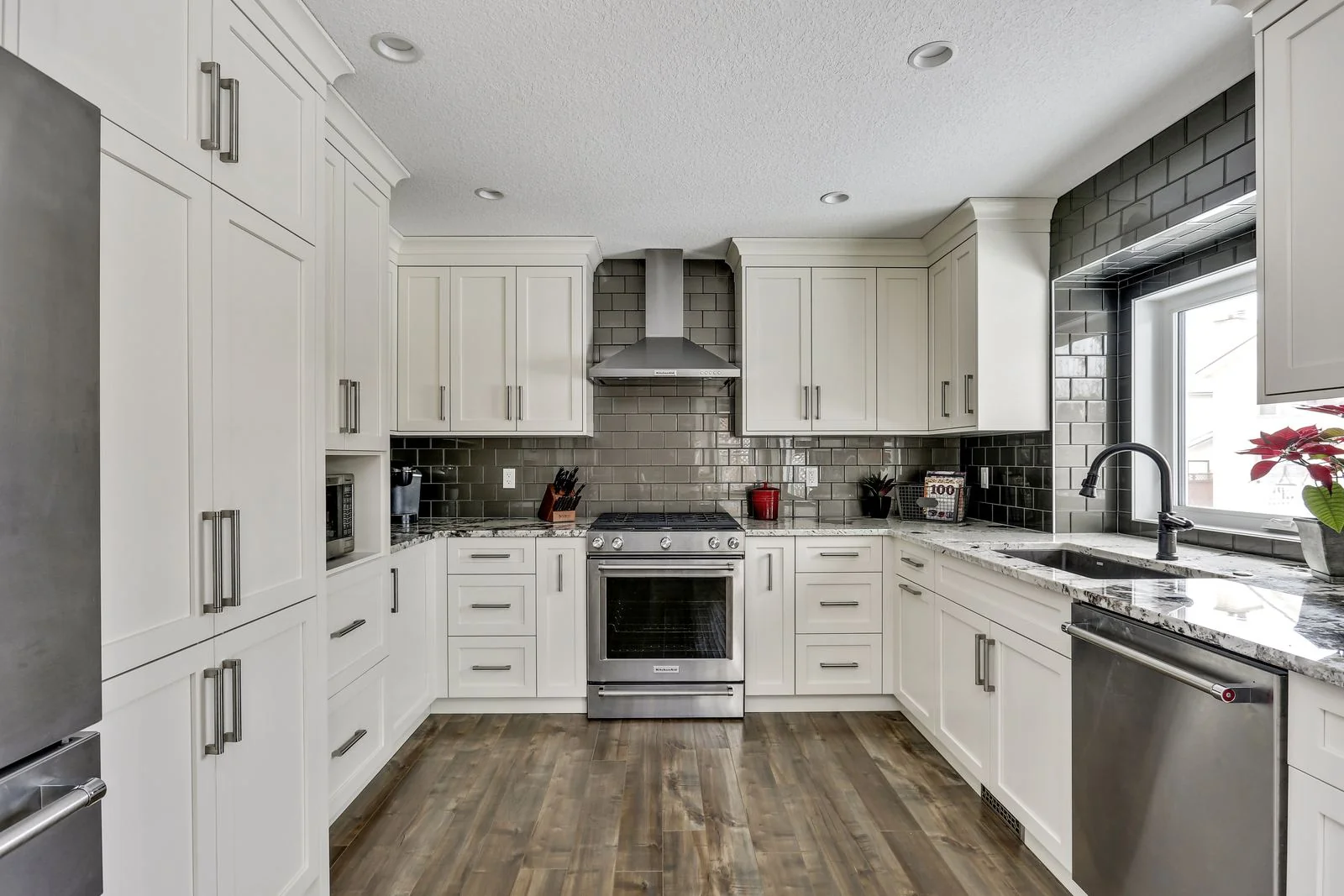 Douglas Dale, Calgary. White kitchen with a grey tiled backsplash and stainless range