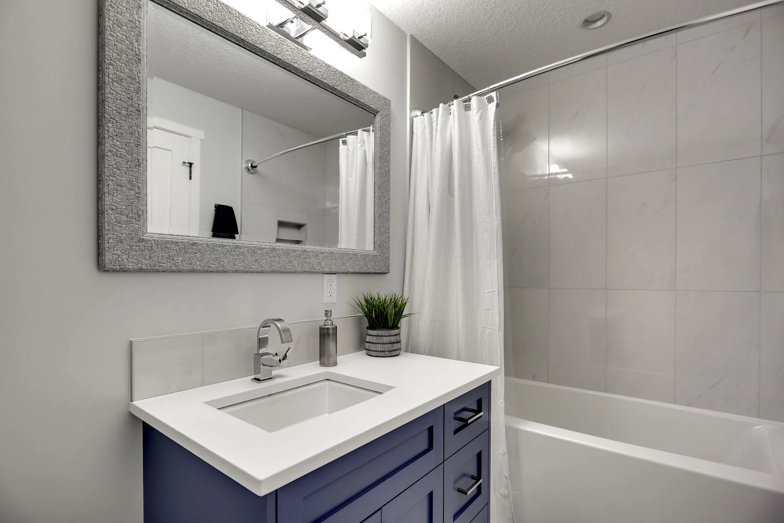 Bathroom vanity in navy with a tiled tub surround