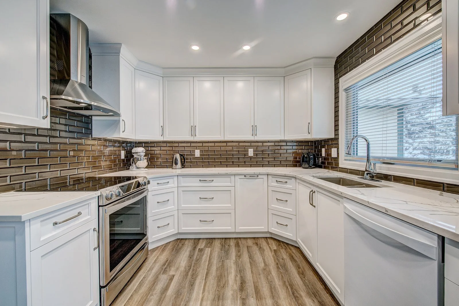 Maxwell, Calgary. Kitchen in white shaker cabinetry with a bronze glass tile backsplash and quartz counters
