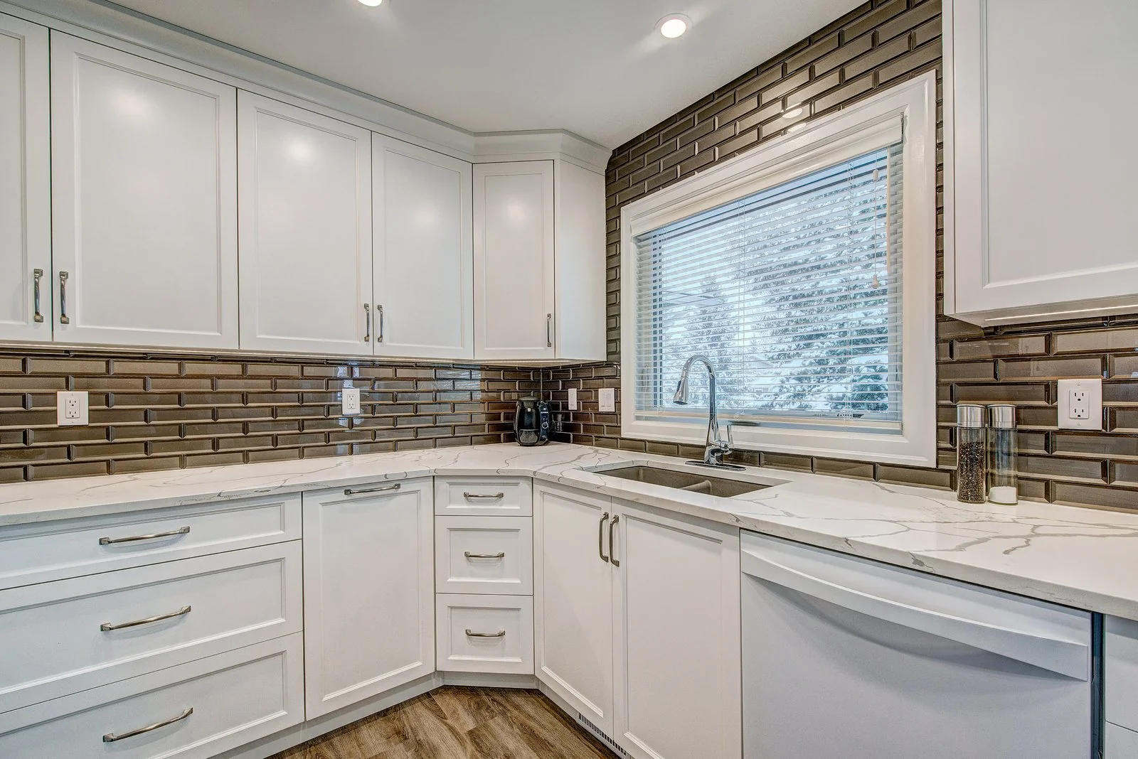 Kitchen corner with the sink under a window and the bronze tile backsplash