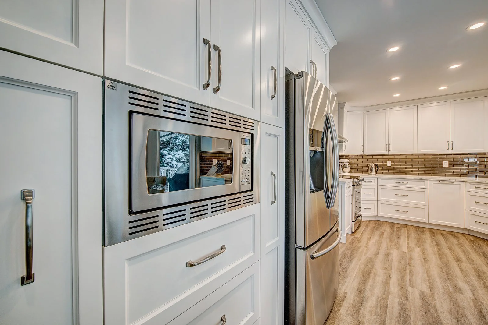Tall cabinetry with a built in microwave beside the refrigerator
