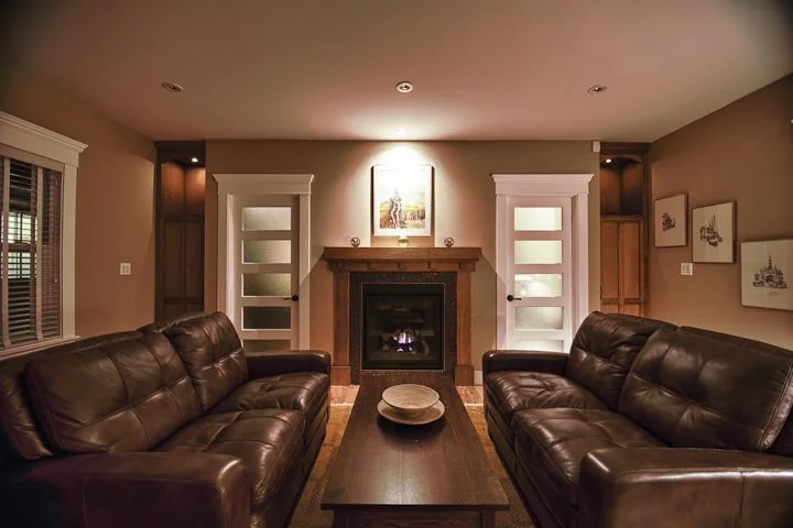 Living room with leather seating facing a fireplace and frosted glass doors