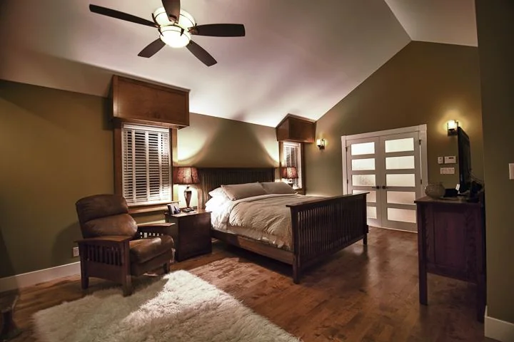 Bedroom under a vaulted ceiling with a ceiling fan and hardwood floor