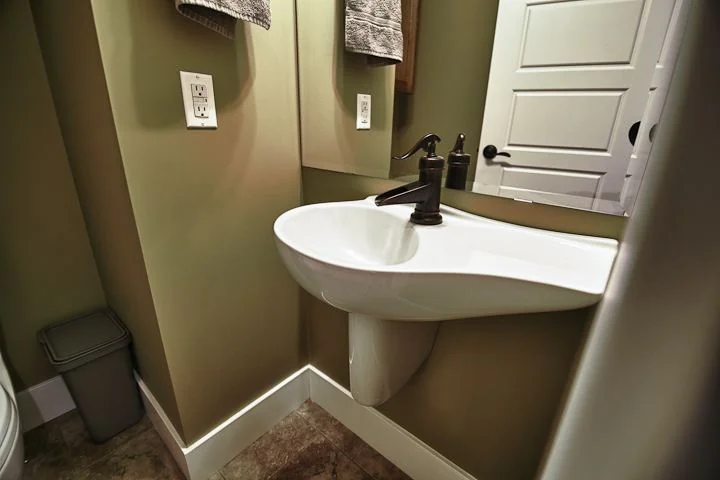 Powder room with a pedestal basin below a framed mirror