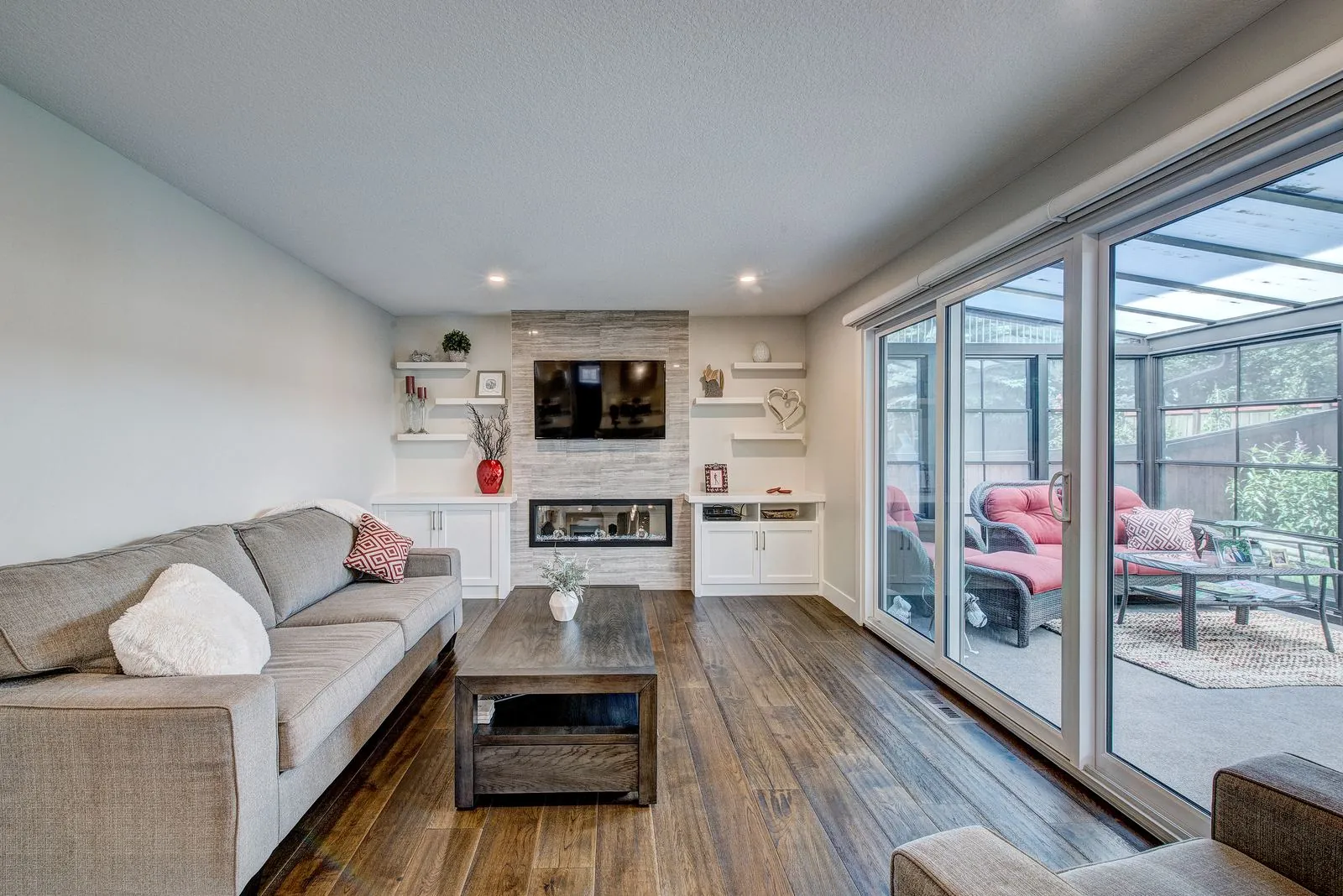 Living room with built in shelving and the sunroom beyond