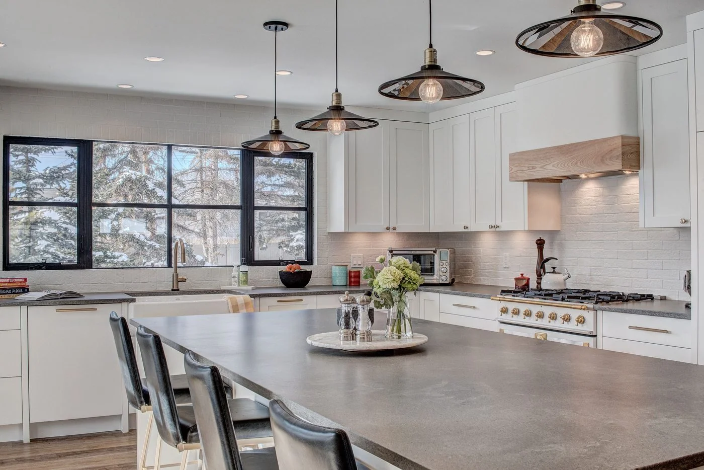 Kitchen island in a concrete toned counter with black framed windows