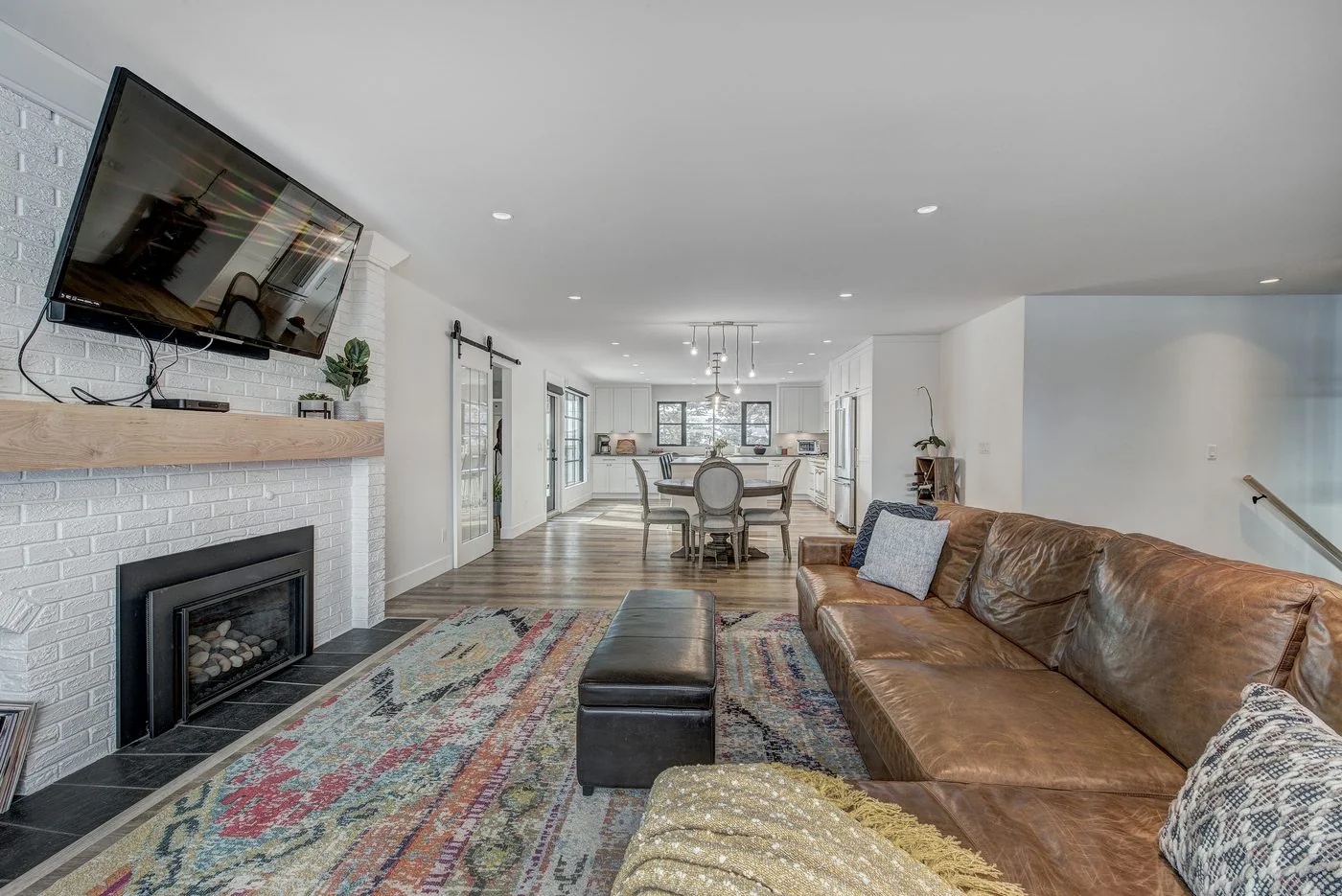 Living room with a white brick fireplace opening to the dining area