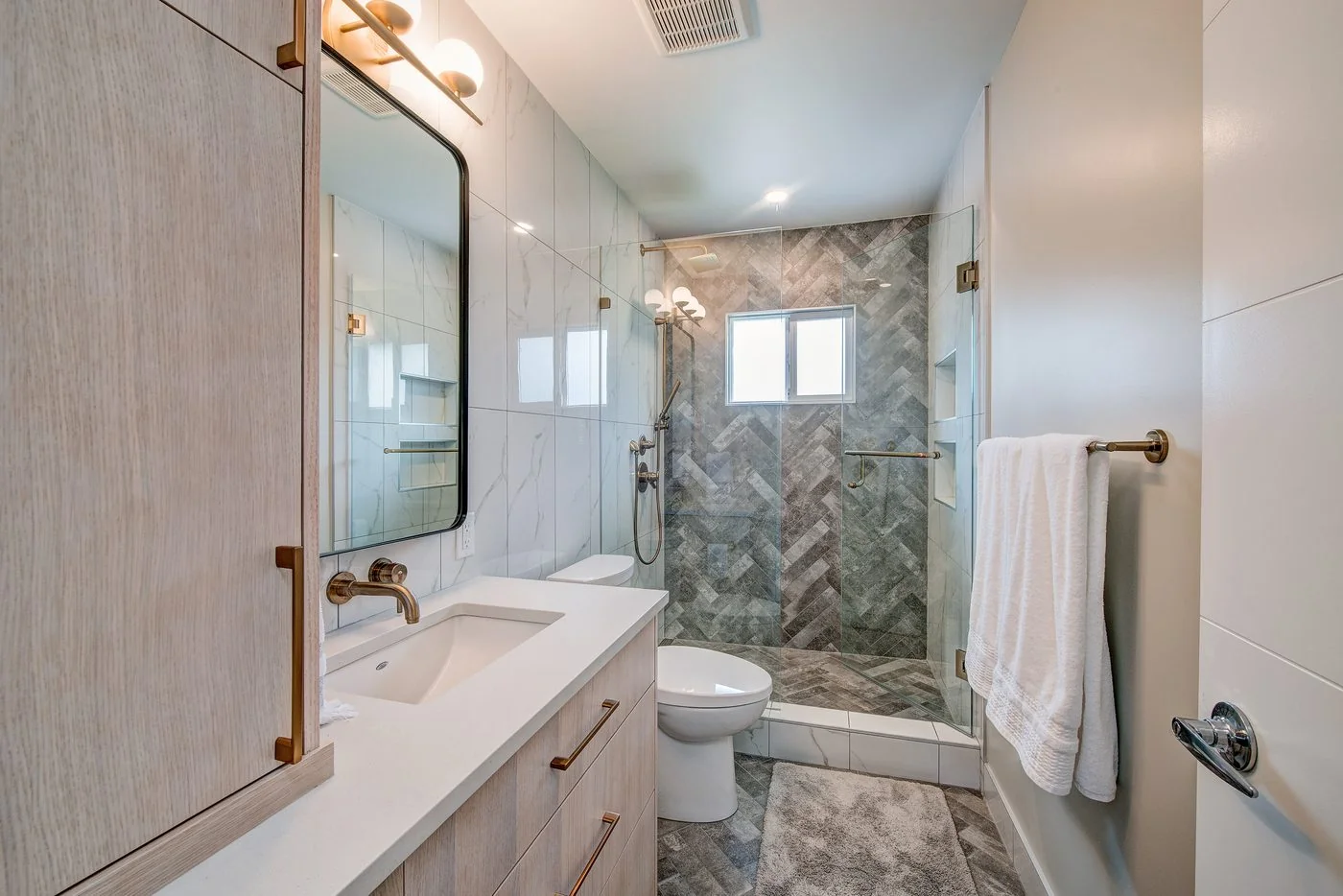 Bathroom vanity with brushed brass fittings beside a tiled shower