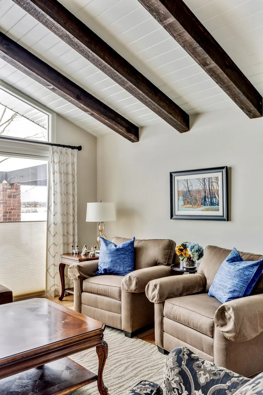 Beamed ceiling meeting a wall of windows in an added living space