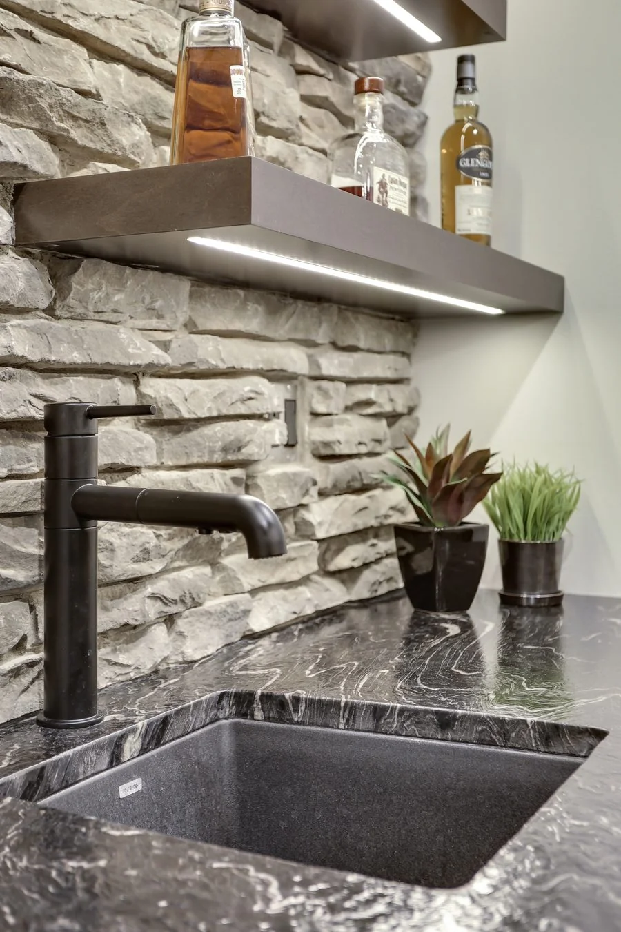 Basement wet bar sink set into a stone feature wall