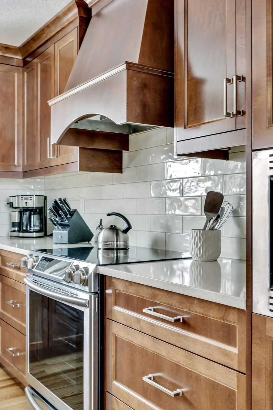 Wood range hood above a slide in range and tiled backsplash