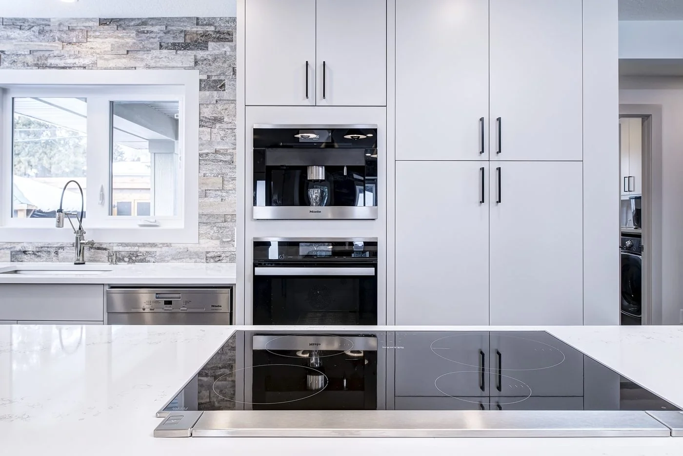 Renovated kitchen with stone backsplash and integrated appliances